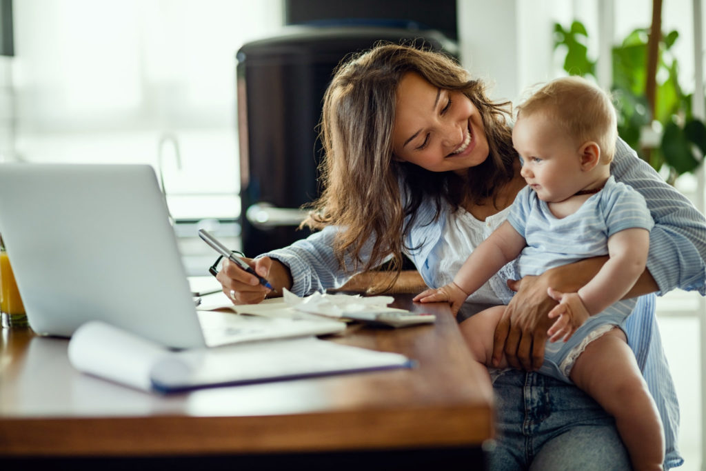 happy mom with baby at table with computer